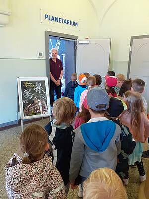Kinder werden vom Dozenten im Planetarium begrüßt